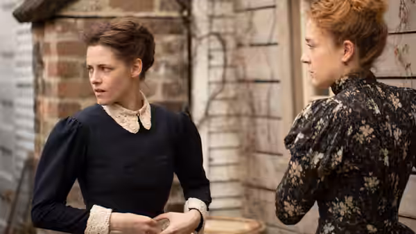 Bridget Sullivan (Kristen Stewart) and Lizzie Borden stand outside a brick house