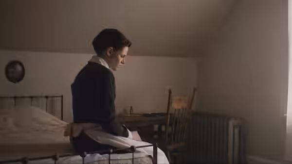 Bridget Sullivan (Kristen Stewart) sits on a bed in a sparse bedroom