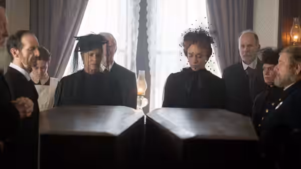 Lizzie Borden (Chloë Sevigny) sits at a table during a formal gathering