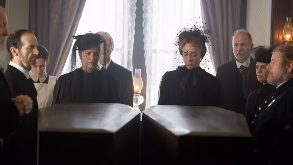 Lizzie Borden (Chloë Sevigny) sits at a table during a formal gathering