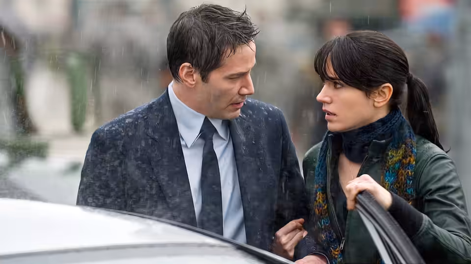 Klaatu (Keanu Reeves) and Helen Benson (Jennifer Connelly) talking by a car in the rain