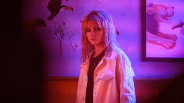Sandie (Anya Taylor-Joy) standing in a room with purple lighting and peeling walls