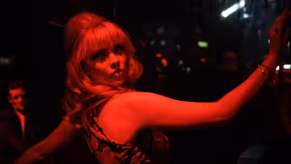 Sandie (Anya Taylor-Joy) reaching out an arm on a red-lit dance floor