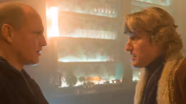 Woody Harrelson facing Owen Wilson in conversation inside a bar