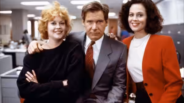 Tess McGill (Melanie Griffith) and Jack Trainer (Harrison Ford) pose with Katharine Parker (Sigourney Weaver) in an office
