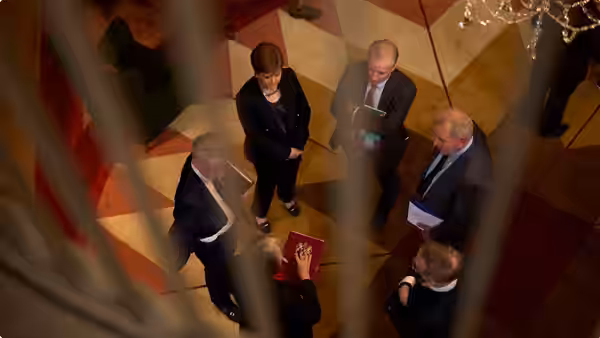 Group of suited figures standing on a geometric patterned floor