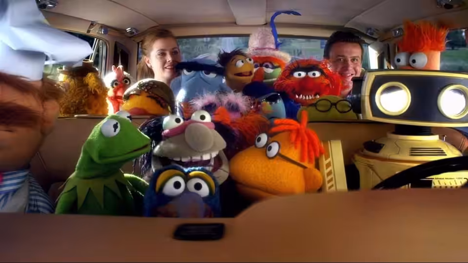 Gary (Jason Segel) and Mary (Amy Adams) ride in a car crowded with Muppets