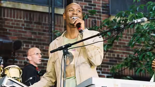 A man singing into a microphone on stage beside a keyboard player