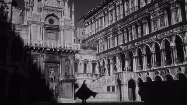 A cloaked figure walks across an empty ornate courtyard at night