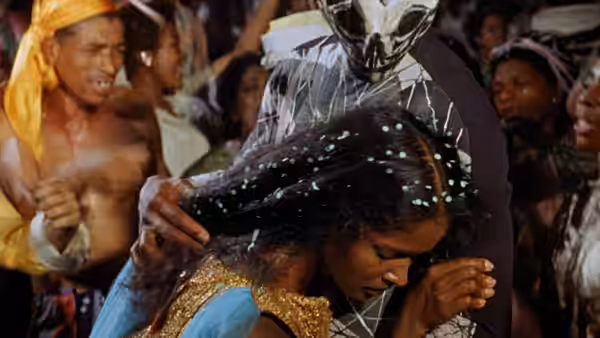 A woman dances beneath a masked reveler as partygoers gather around them