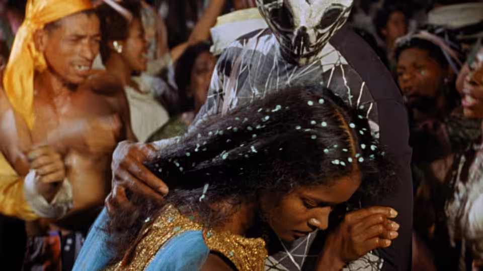 A woman dances beneath a masked reveler as partygoers gather around them