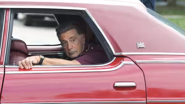 Jimmy Hoffa (Al Pacino) leaning from the window of a red car