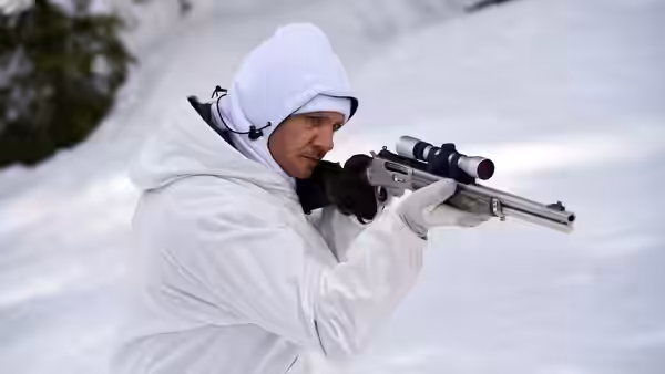 Cory Lambert (Jeremy Renner) aims a rifle while wearing winter gear