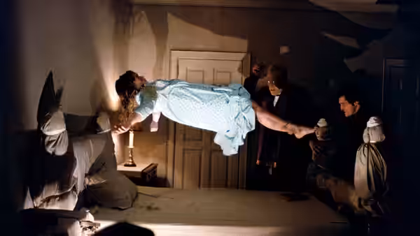 Regan MacNeil (Linda Blair) levitates above the bed held by priests and figures in white