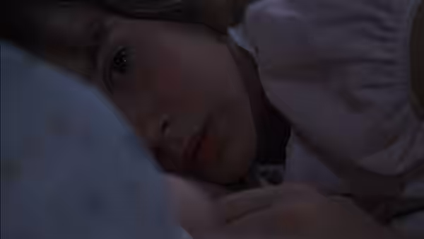 Regan MacNeil (Linda Blair) rests in bed looking upward with a weary expression