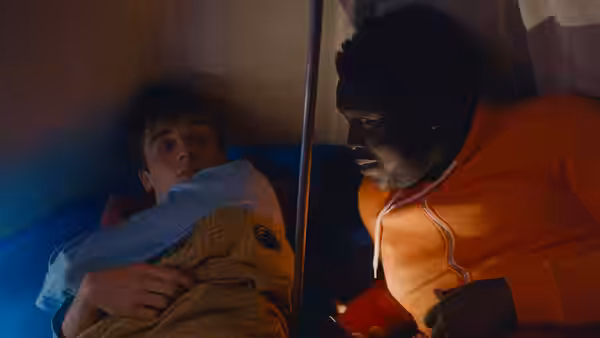 Two men lie in bunk beds facing each other in a small room