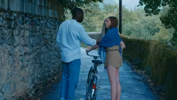 A man and a woman stand facing each other next to a bicycle