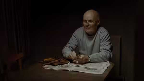Dan (Dave Johns) eating fish and chips at a table with an open newspaper