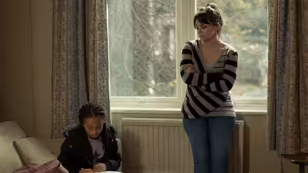 Katie (Hayley Squires) standing with arms crossed while Daisy draws on the floor