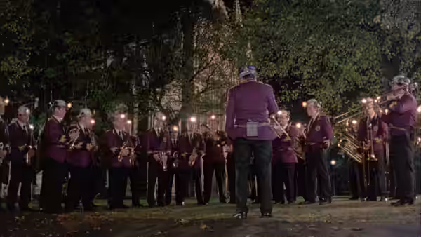 A brass band playing at night in a park lit by lamps