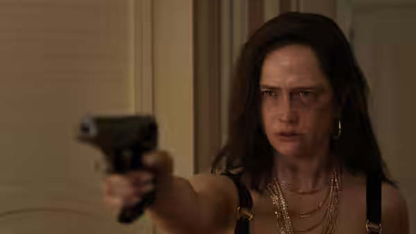Nora Wolfe (Eva Green) pointing a pistol forward with a bruised face