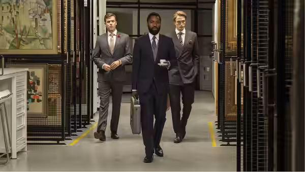 Protagonist (John David Washington) carrying a briefcase while walking through an art vault
