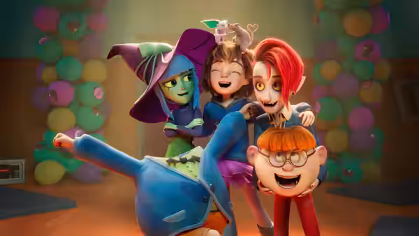 Four costumed children hugging and posing together amid colorful balloon decorations
