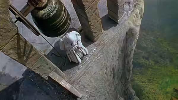 A nun crouched on a high ledge near a large hanging bell
