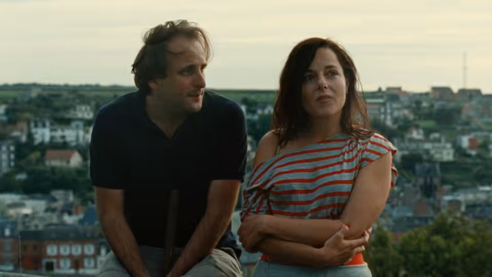 Sylvain (Vincent Macaigne) and Patricia (Laure Calamy) sitting on a rooftop overlooking the town