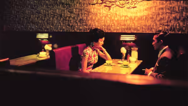 Su Li-zhen (Maggie Cheung) and Chow Mo-wan (Tony Leung) converse at a restaurant table