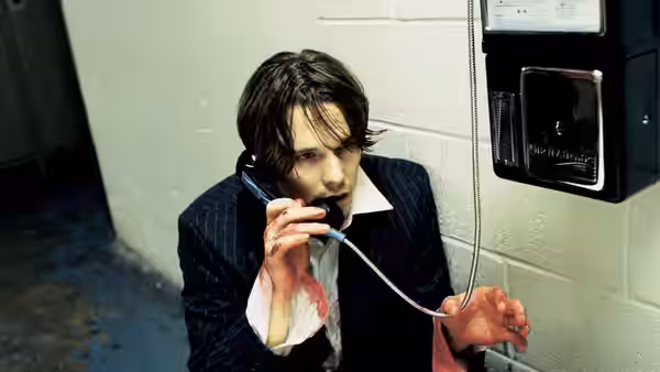 Hamlet (Ethan Hawke) speaking on a payphone with bloodied hands and shirt