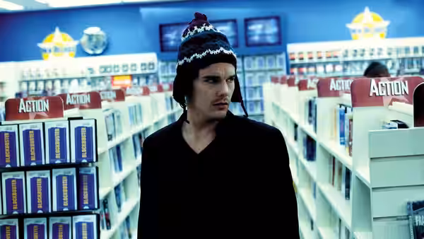Hamlet (Ethan Hawke) standing in a video store aisle wearing a knitted hat