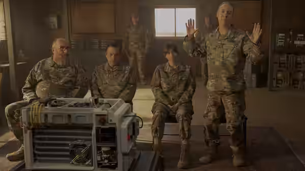 Soldiers in camouflage gathered around equipment inside a large warehouse space