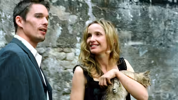Jesse (Ethan Hawke) and Céline (Julie Delpy) with a cat against a stone wall