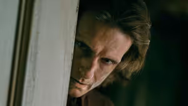 Jim Matthews (Eion Bailey) peering intently from behind a doorway