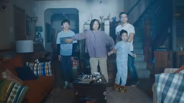 Woman in purple sweater gestures widely in living room with boy man and girl