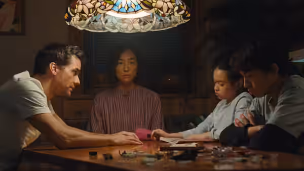 Man woman and two children sit at wooden table with small objects