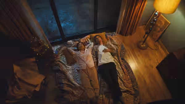 Man and woman lie on bed in bedroom looking up at ceiling