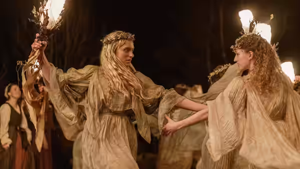 Two women dancing with flaming torches in a nighttime gathering