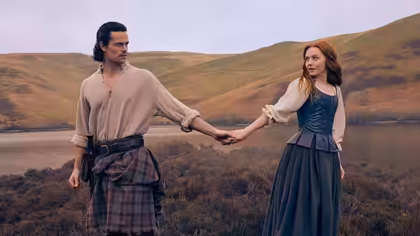 Man and woman holding hands on a moor beside a body of water