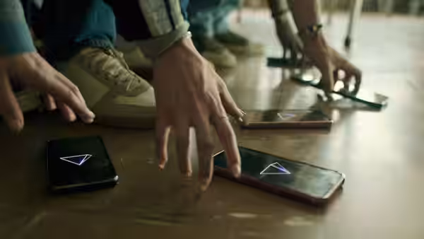 Hands reach for smartphones displaying glowing triangle symbols on floor