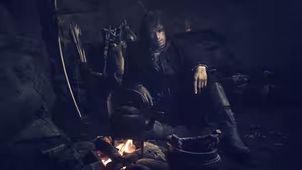 Jamie Fraser (Sam Heughan) tending a kettle over a fire in a cave