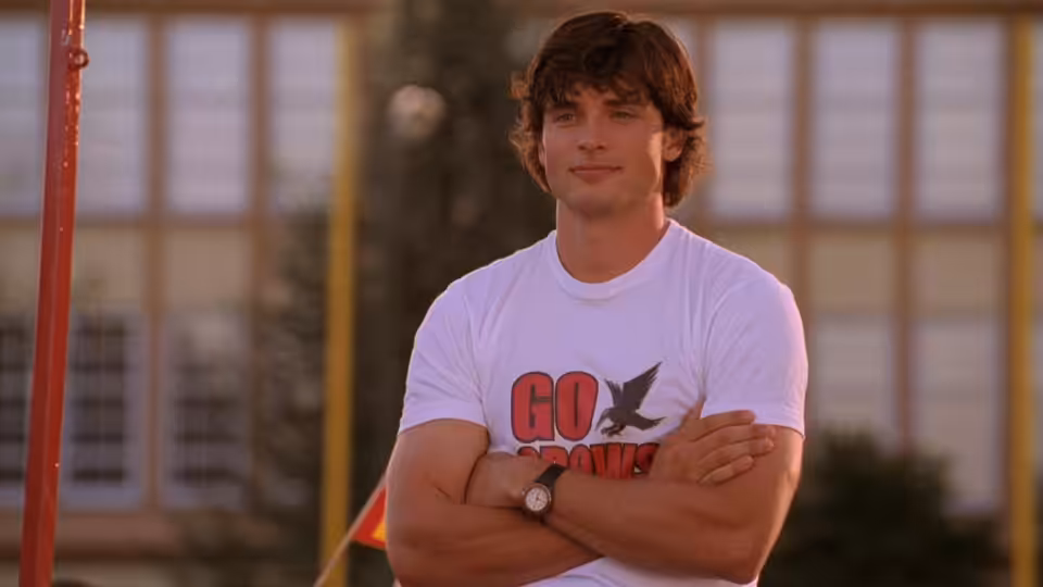Clark Kent (Tom Welling) stands with arms crossed outside a school