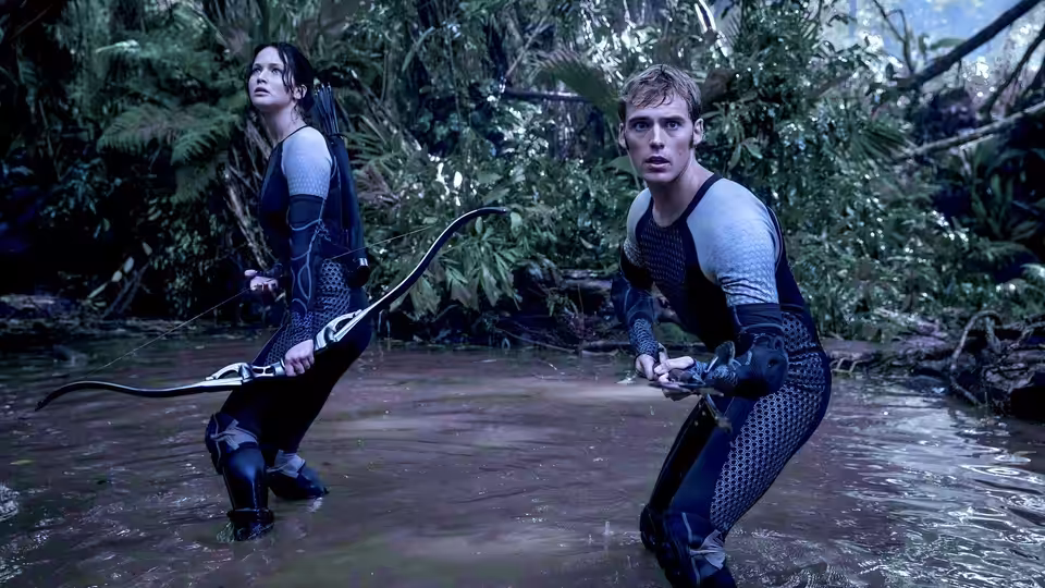 Katniss Everdeen (Jennifer Lawrence) and Peeta Mellark (Josh Hutcherson) crouched in jungle water