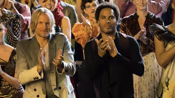 Two men clapping their hands before a smiling audience in formal attire
