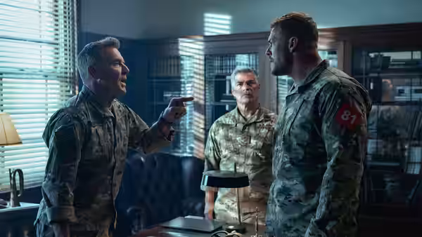 81 (Alan Ritchson) facing a pointing officer during an argument in an office