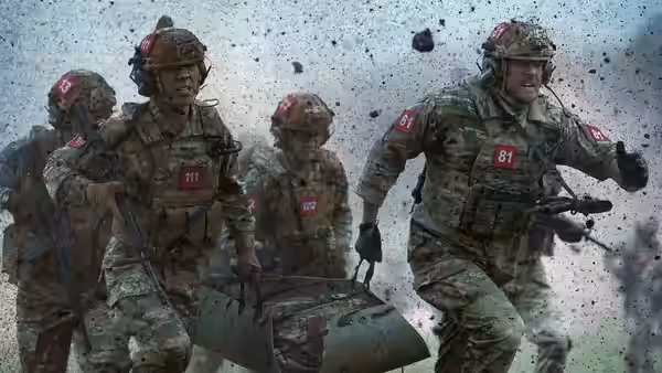 Soldiers in camouflage running through dust while carrying gear and weapons