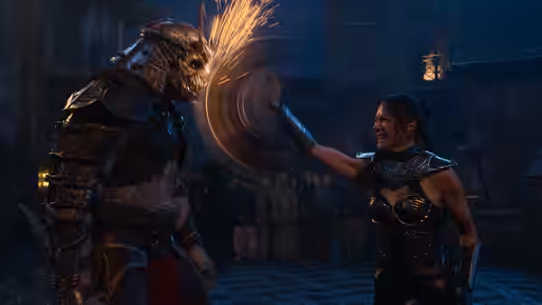 Kitana (Adeline Rudolph) wielding a spinning blade against an armored foe in a stone arena