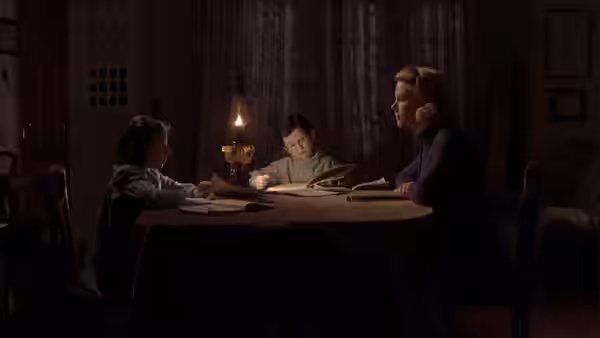 Grace Stewart (Nicole Kidman) and her children read by lamplight at the table