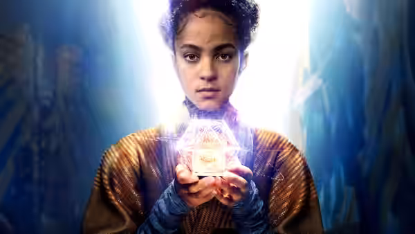 Gaal Dornick (Lou Llobell) holds a glowing holographic cube in both hands